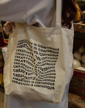 Load image into Gallery viewer, Artistic tote bag with "Creativity Is Contagious" on it